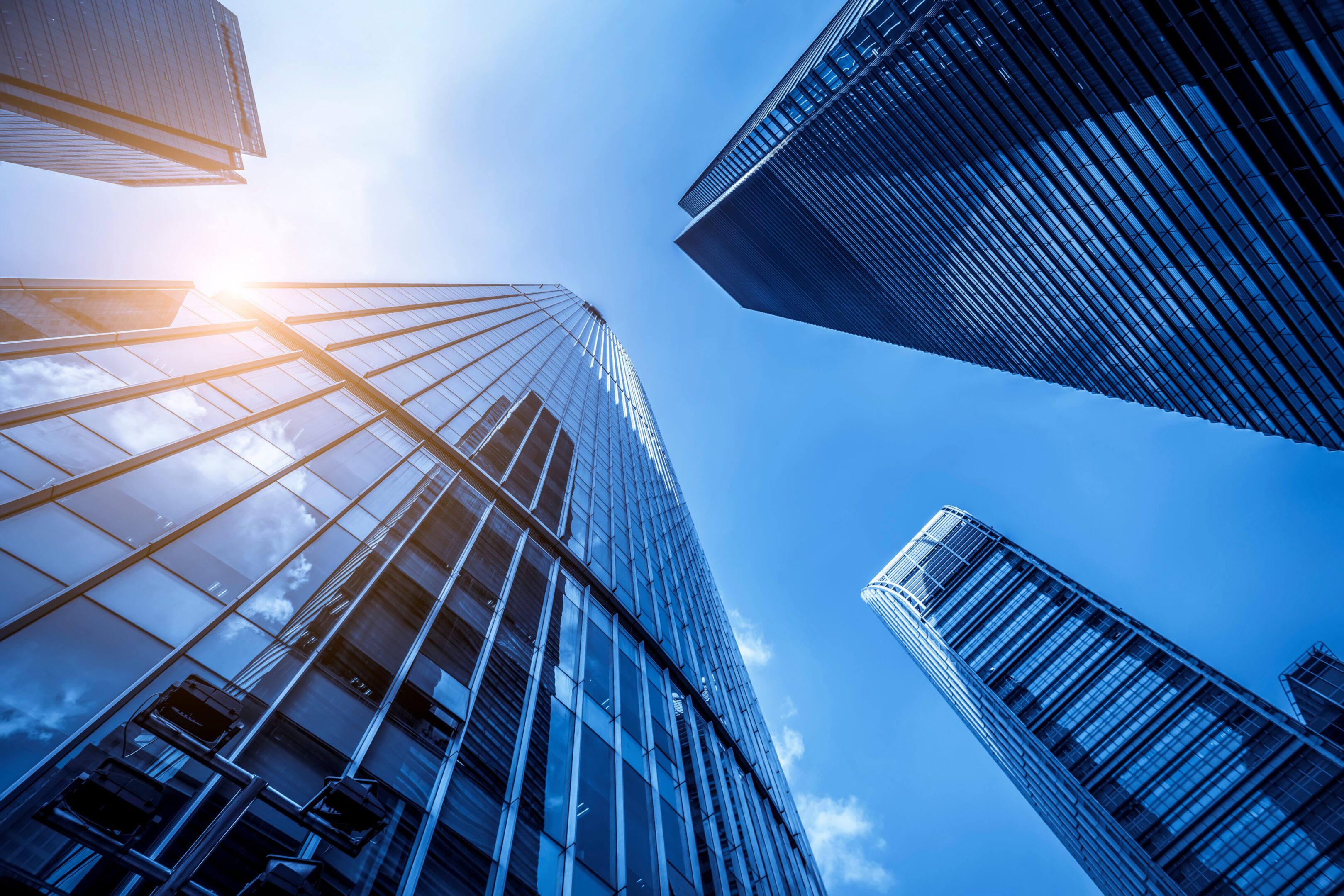 Looking up at modern skyscrapers against a clear blue sky.